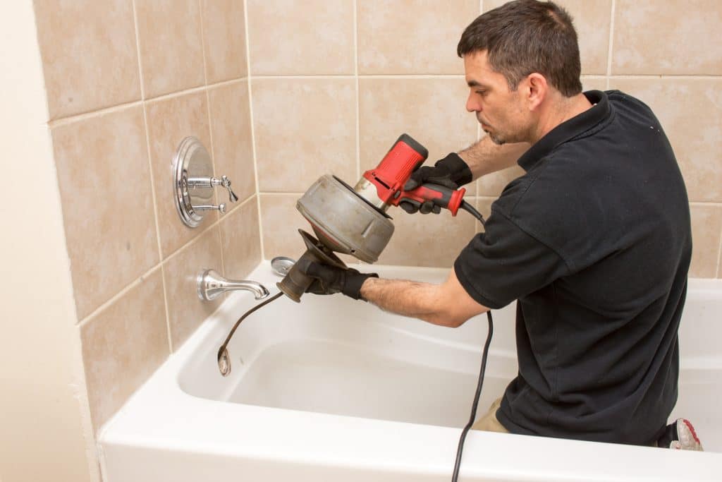 Plumber unclogging a tub drain